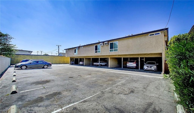 exterior space featuring covered and uncovered parking and fence