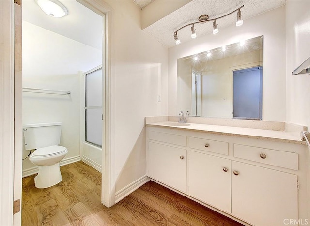 bathroom with a textured ceiling, vanity, toilet, and wood finished floors