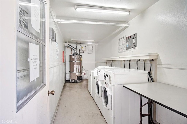 common laundry area featuring light floors, washing machine and dryer, and strapped water heater