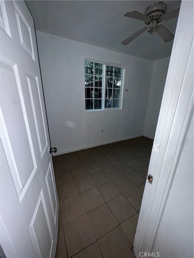 unfurnished room featuring ceiling fan and dark tile patterned flooring