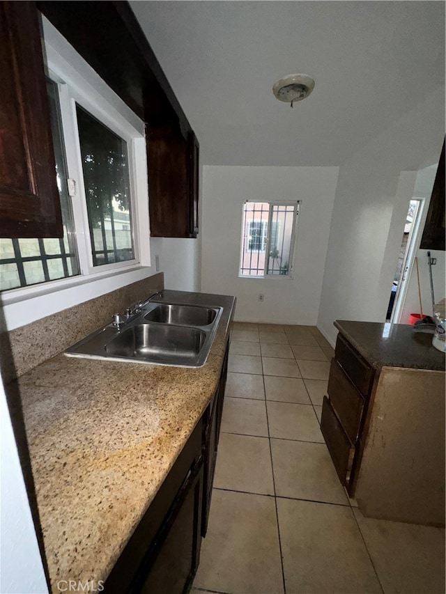 kitchen with light tile patterned floors, dark brown cabinets, and sink