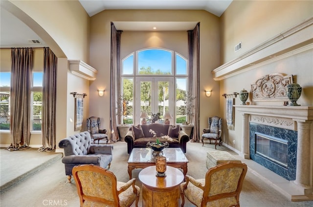 carpeted living room with a fireplace, plenty of natural light, high vaulted ceiling, and french doors