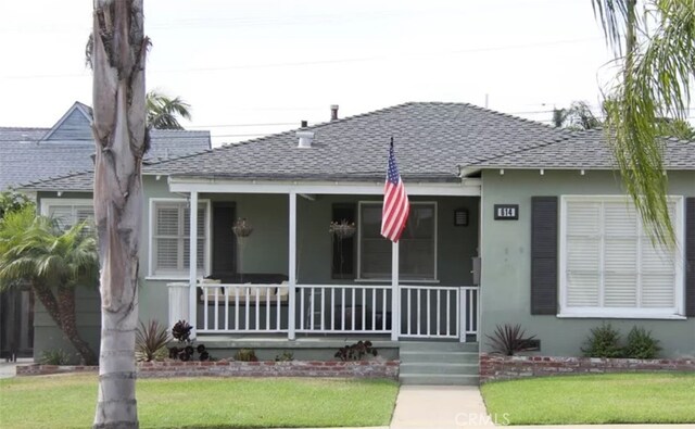 bungalow featuring covered porch and a front yard