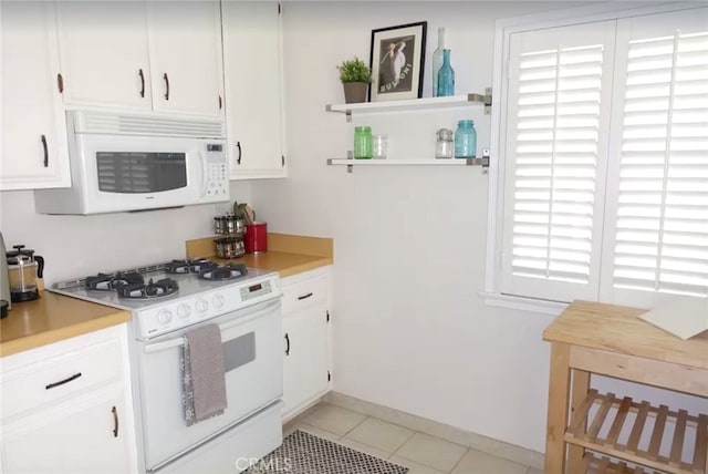 kitchen with light tile patterned floors, white appliances, and white cabinets