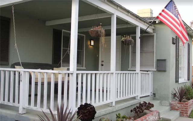 view of exterior entry featuring covered porch