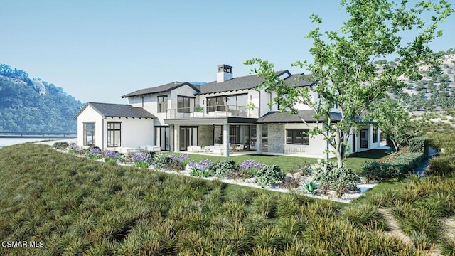 rear view of house featuring a patio area, a balcony, and a lawn