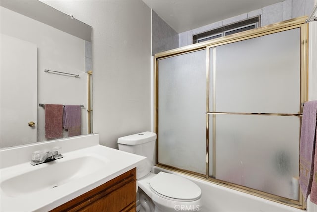 full bathroom with enclosed tub / shower combo, vanity, and toilet