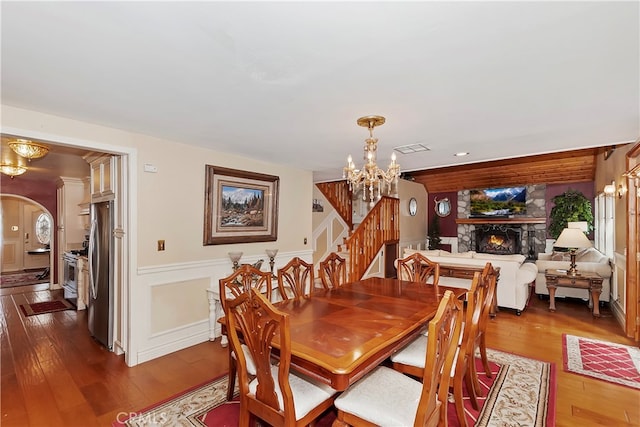 dining area with hardwood / wood-style flooring, a fireplace, and a notable chandelier