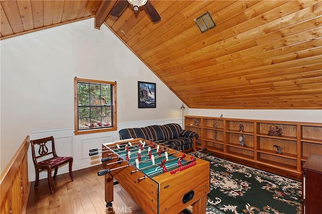 playroom with ceiling fan, wainscoting, hardwood / wood-style floors, vaulted ceiling with beams, and wood ceiling