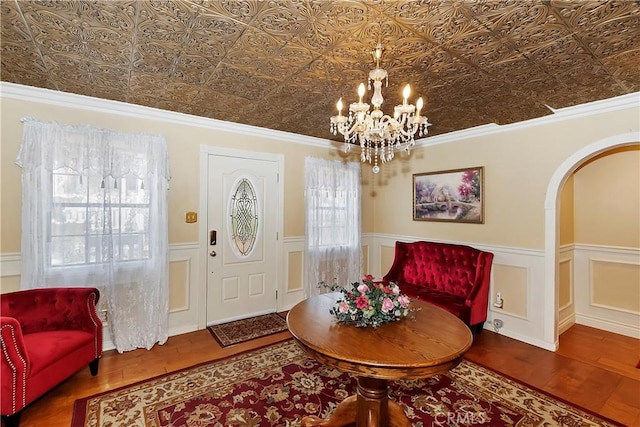 entryway with an inviting chandelier, arched walkways, an ornate ceiling, and a wainscoted wall
