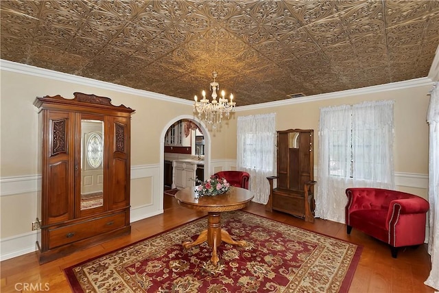 foyer entrance featuring visible vents, arched walkways, wood finished floors, a wainscoted wall, and a notable chandelier