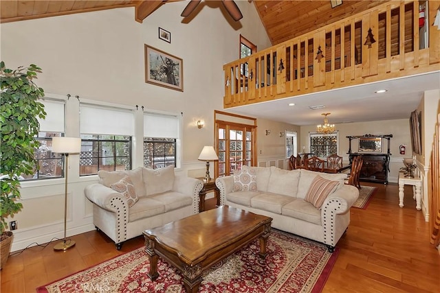 living area featuring wood-type flooring, wood ceiling, ceiling fan with notable chandelier, and a wealth of natural light