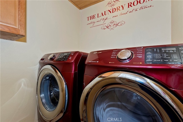 clothes washing area with cabinets and washing machine and dryer