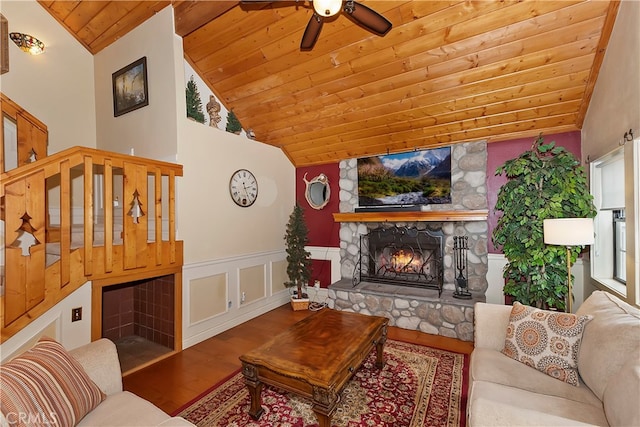 living room with wood ceiling, high vaulted ceiling, hardwood / wood-style floors, a stone fireplace, and ceiling fan