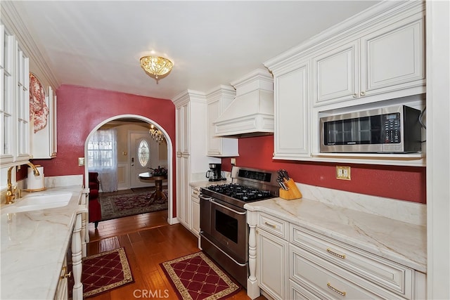 kitchen featuring light stone counters, sink, stainless steel appliances, and dark wood-type flooring