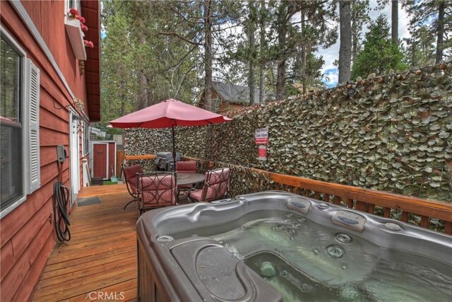 wooden deck with a hot tub and outdoor dining space