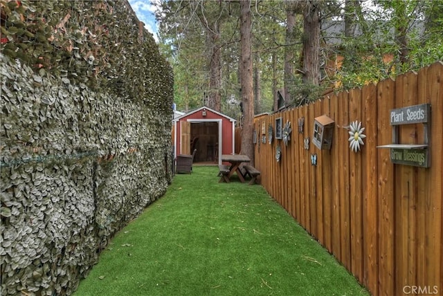 view of yard featuring fence, an outbuilding, and a shed