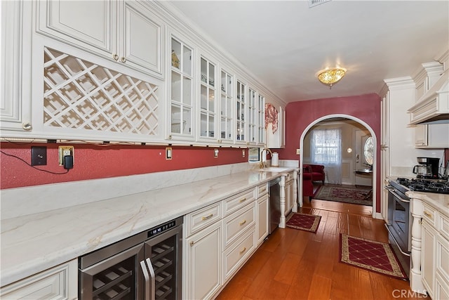 kitchen with white cabinets, beverage cooler, stainless steel appliances, dark hardwood / wood-style floors, and light stone countertops