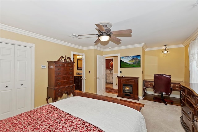 carpeted bedroom with a closet, ceiling fan, and crown molding