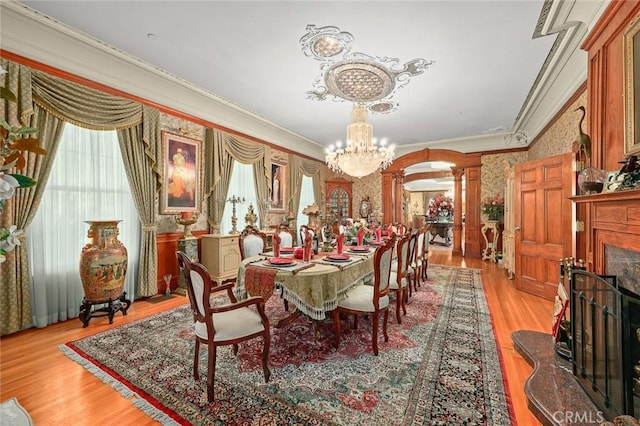 dining area with a chandelier, light hardwood / wood-style floors, ornate columns, and crown molding