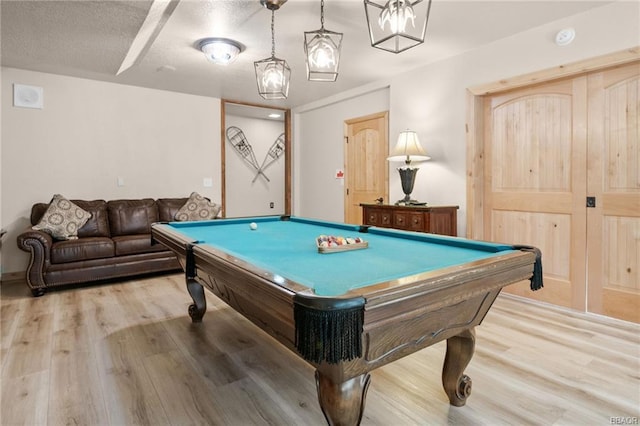 game room featuring light hardwood / wood-style floors, a textured ceiling, and pool table