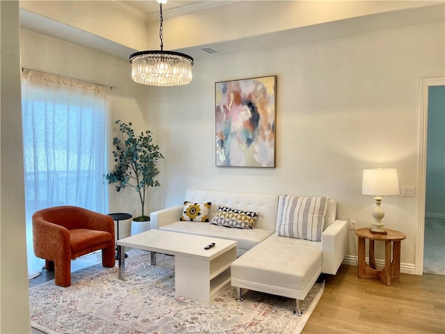 living room featuring light hardwood / wood-style floors, crown molding, and an inviting chandelier