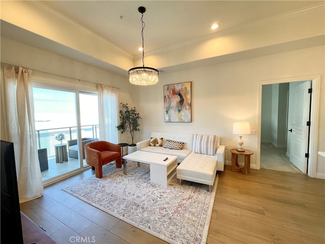 living room featuring ornamental molding, a chandelier, and light hardwood / wood-style floors