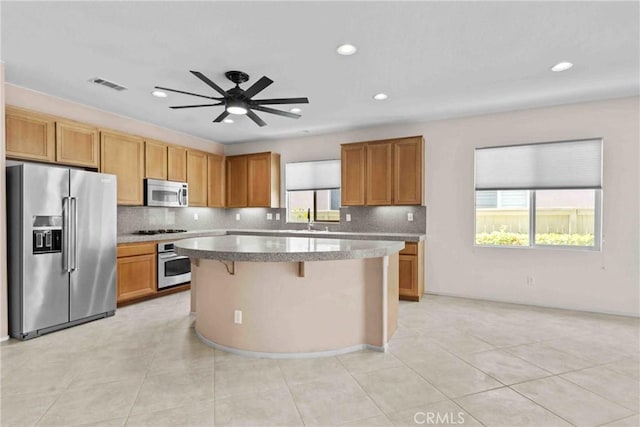 kitchen featuring a sink, a kitchen island, visible vents, light countertops, and appliances with stainless steel finishes