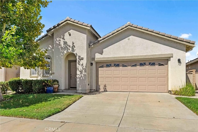 mediterranean / spanish-style house with a front yard, driveway, an attached garage, and stucco siding