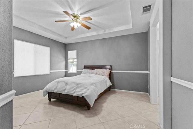 bedroom with light tile patterned floors, visible vents, and a raised ceiling