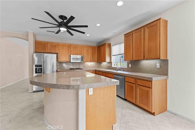 kitchen with decorative backsplash, stainless steel appliances, a sink, and a center island