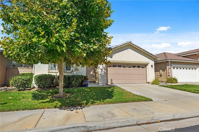 view of front of home featuring a garage, concrete driveway, stucco siding, a tile roof, and a front yard