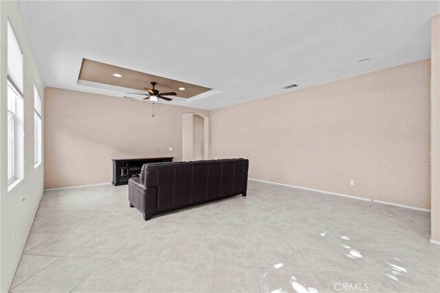 living room with a tray ceiling and ceiling fan