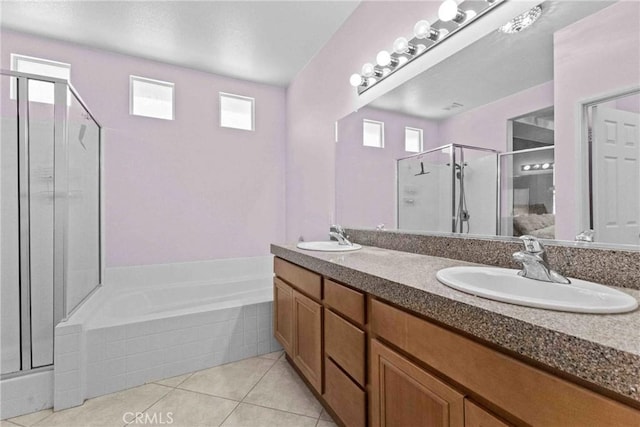 full bath with a stall shower, double vanity, a sink, and tile patterned floors