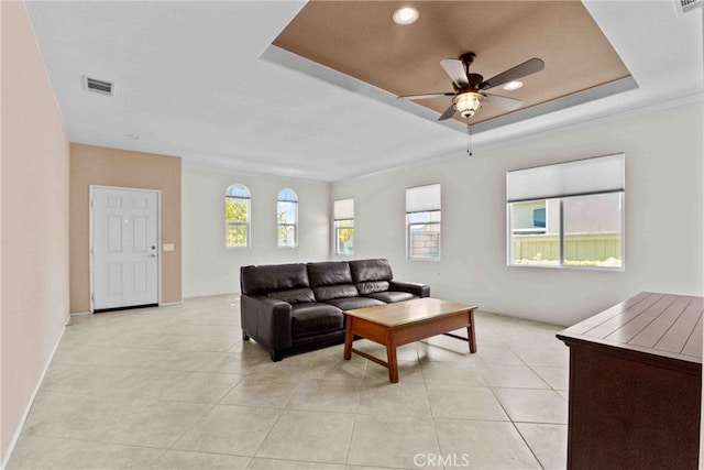 tiled living room featuring a tray ceiling, ceiling fan, and a healthy amount of sunlight