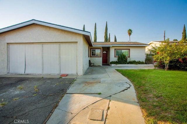 ranch-style home featuring a garage, stucco siding, driveway, and a front yard