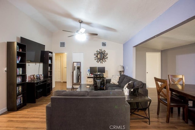 living room featuring a ceiling fan, visible vents, vaulted ceiling, and wood finished floors