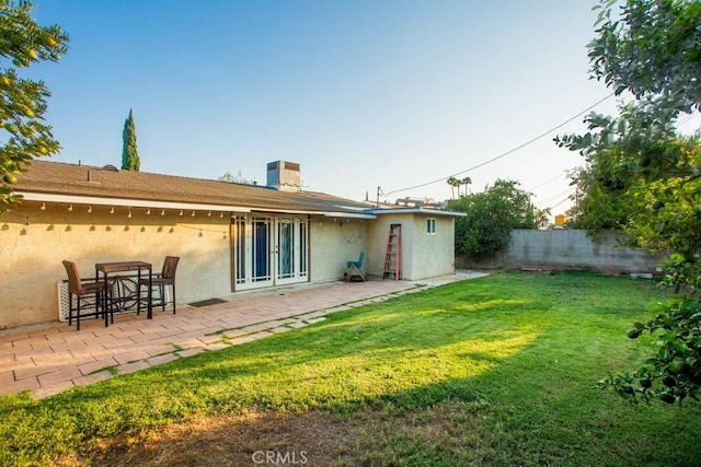 back of house featuring a lawn, a patio area, fence, and stucco siding