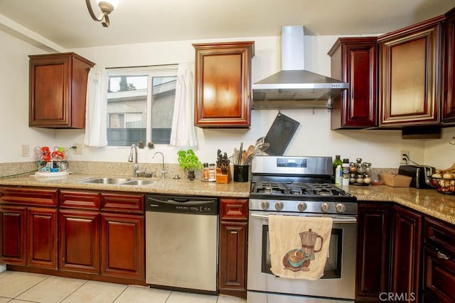 kitchen featuring appliances with stainless steel finishes, a sink, dark brown cabinets, light stone countertops, and wall chimney exhaust hood