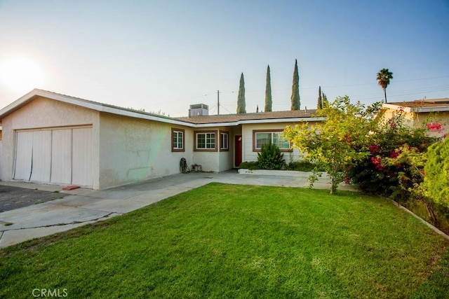 view of front facade featuring a front yard, central AC, an attached garage, and stucco siding