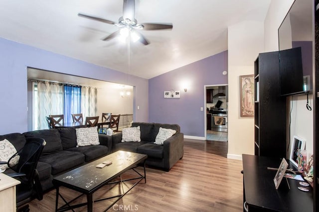 living area with a ceiling fan, vaulted ceiling, light wood-style flooring, and baseboards