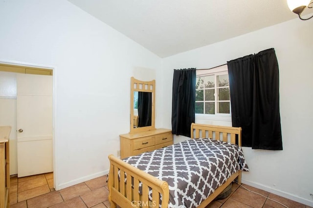 bedroom featuring vaulted ceiling, light tile patterned floors, and baseboards