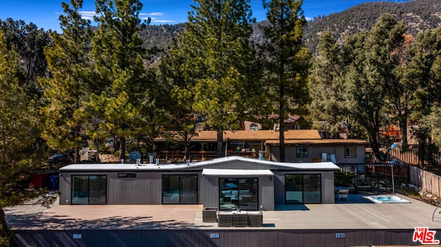 back of property with a deck with mountain view and a hot tub