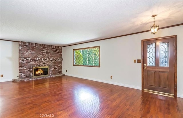 unfurnished living room with a brick fireplace, ornamental molding, dark hardwood / wood-style floors, and a textured ceiling