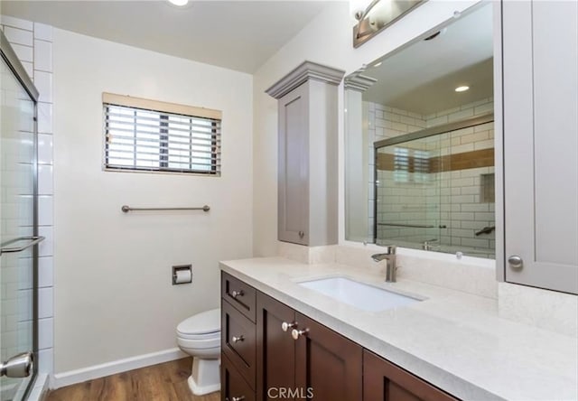 bathroom featuring hardwood / wood-style flooring, vanity, walk in shower, and toilet