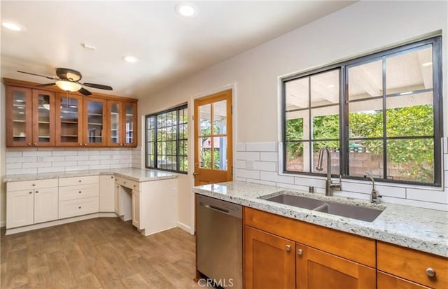 kitchen with sink, dishwasher, light stone counters, tasteful backsplash, and light wood-type flooring