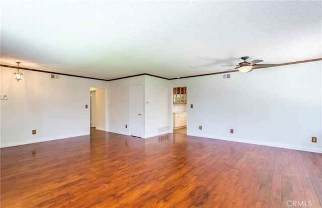 spare room with crown molding, dark wood-type flooring, a textured ceiling, and ceiling fan