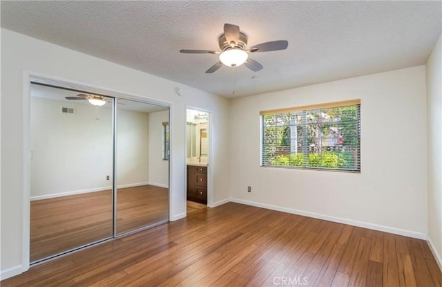 unfurnished bedroom with ceiling fan, a closet, wood-type flooring, and a textured ceiling