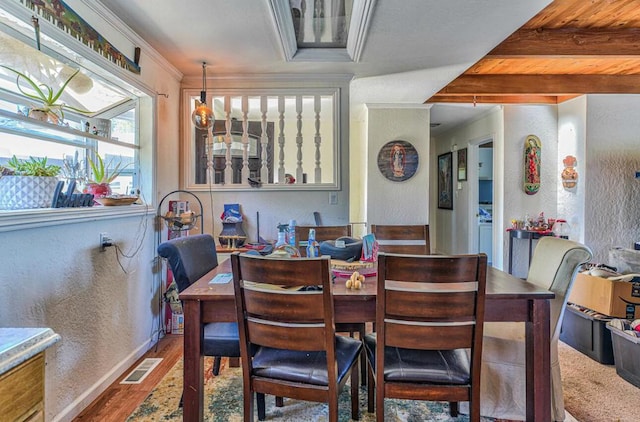 dining space featuring a notable chandelier, beam ceiling, hardwood / wood-style flooring, and ornamental molding