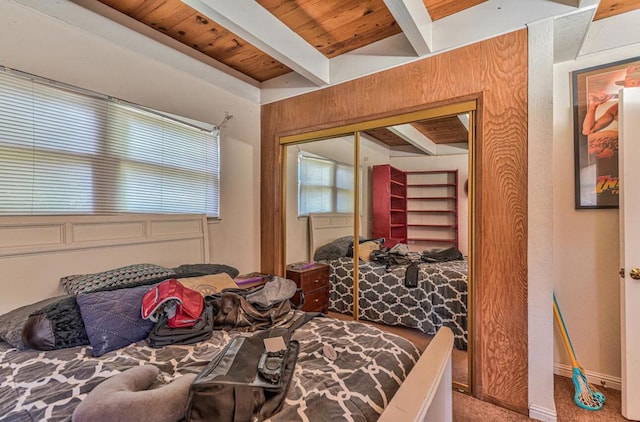 carpeted bedroom featuring a closet, beamed ceiling, and wooden ceiling